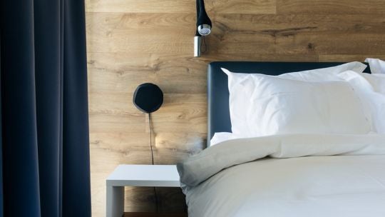 Modern Icelandic hotel room with minimalist Nordic design, floor-to-ceiling windows revealing urban landscape, crisp white linens on sleek platform bed