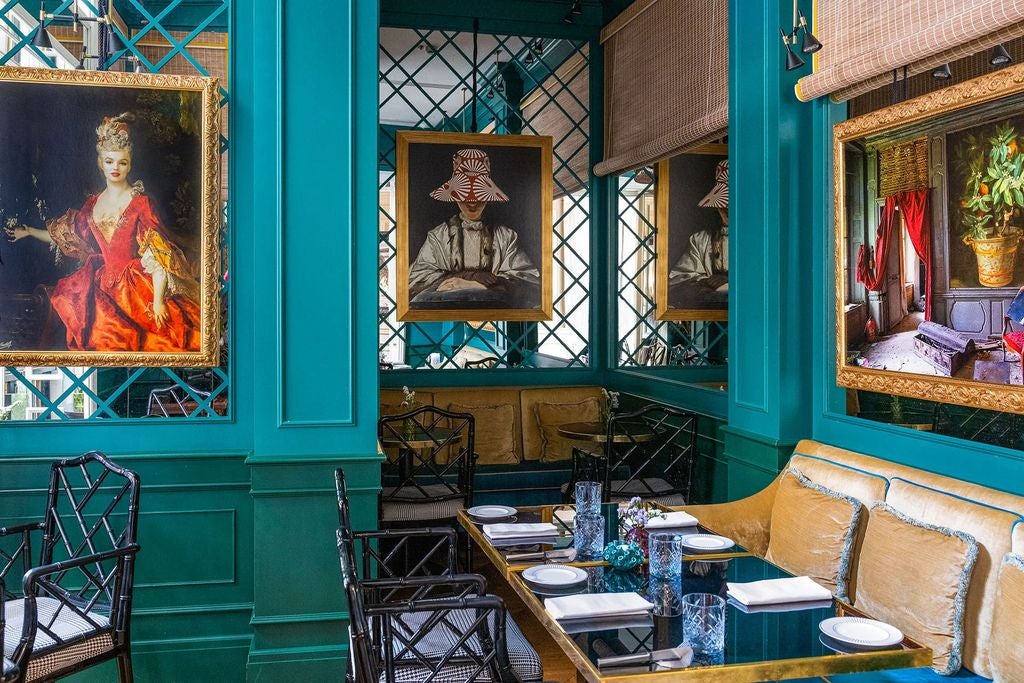 Elegant hotel dining room in Rome with emerald green walls, crystal chandeliers, ornate gold mirrors, and velvet banquette seating