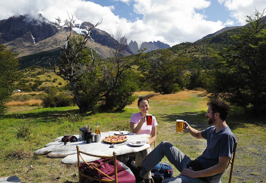 Luxury mountain lodge nestled in Torres del Paine National Park features wooden architecture, vast windows, and stunning Patagonian peaks backdrop