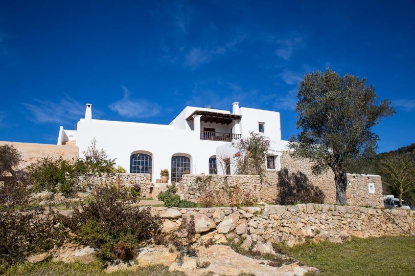 Elegant Spanish countryside hotel with whitewashed walls, stone arches and lush Mediterranean garden featuring a tranquil swimming pool