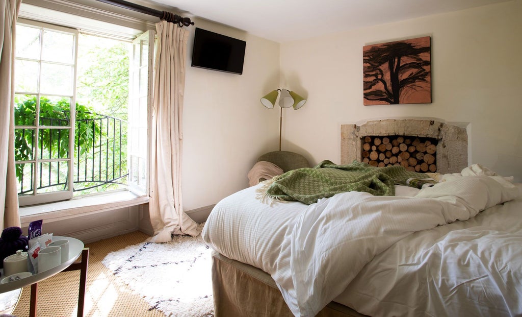 Elegant medium-sized double hotel room at The Beckford Arms, featuring crisp white linens, rustic wooden furniture, and soft natural lighting from large windows.