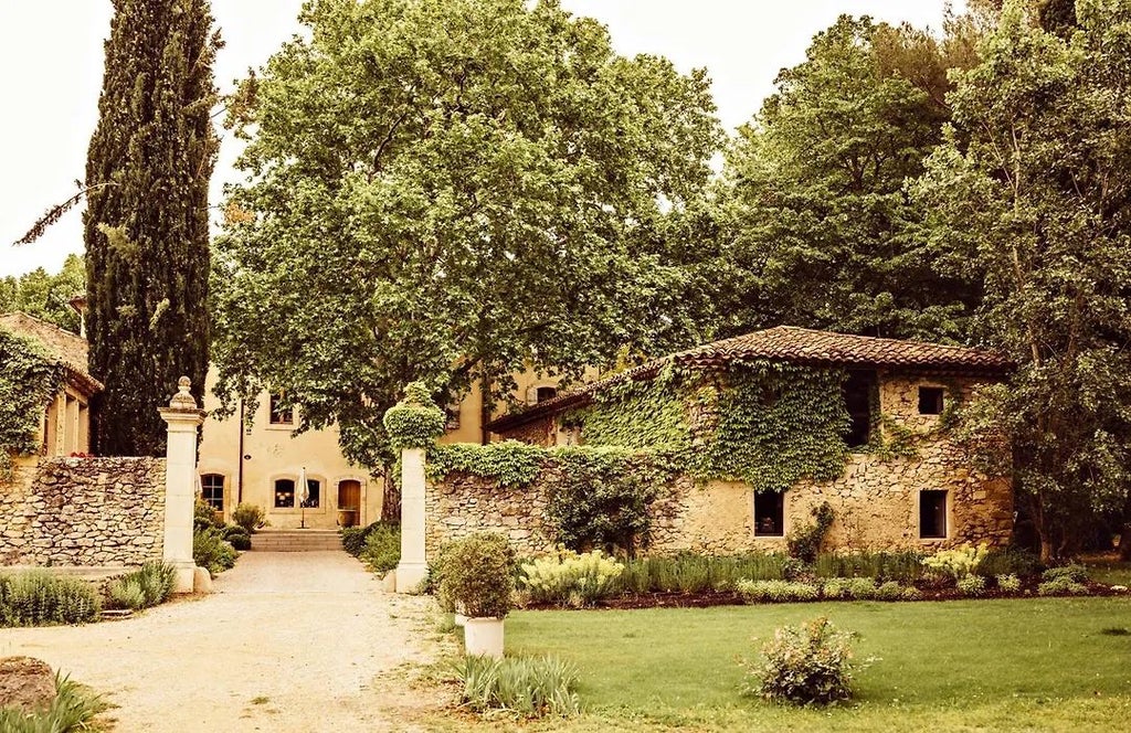 Elegant stone facade of Le Galinier hotel with blue shutters, lavender fields, and Provençal charm nestled in the scenic French countryside landscape