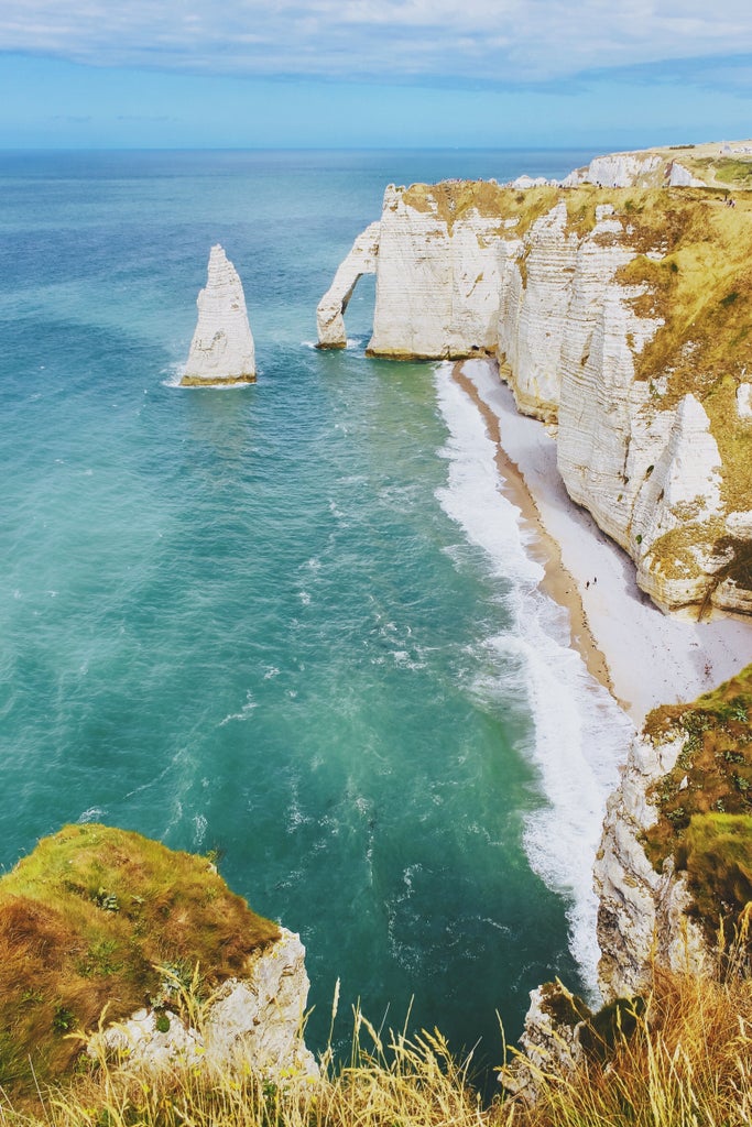 Panoramic view of historic Normandy landing beaches, World War II memorial, and lush coastal landscape with elegant tour group exploring historic sites