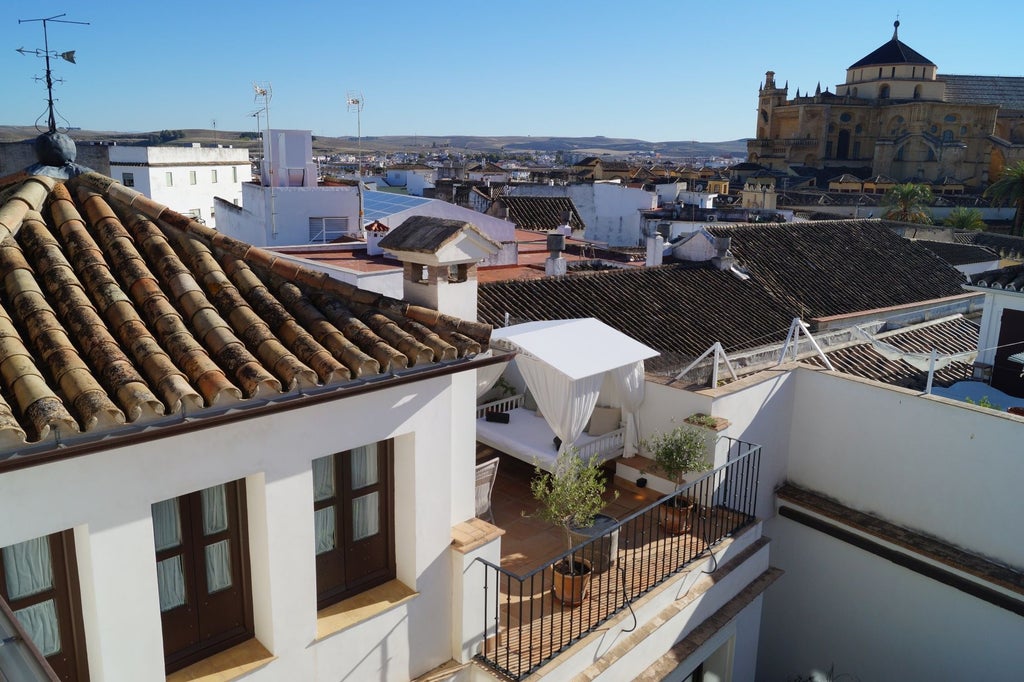 Elegant white-washed historic Spanish hotel with ornate balconies overlooking Córdoba's charming architectural landscape, bathed in warm golden sunlight