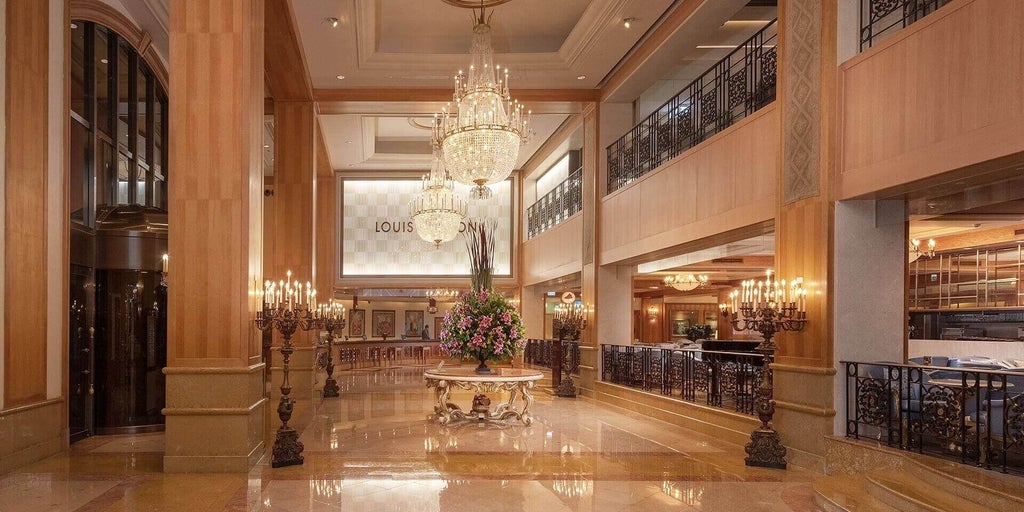 Modern high-rise luxury hotel tower with glass facade, featuring ornate gold and red entrance, situated in downtown Kaohsiung at sunset