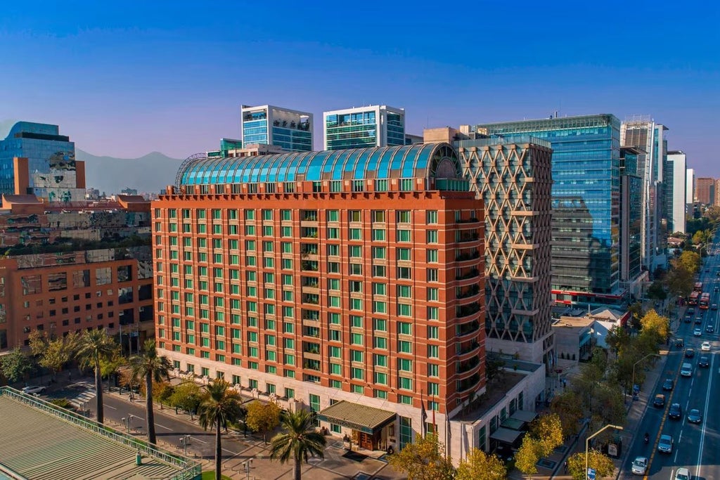 Elegant Ritz-Carlton Santiago hotel exterior with grand stone facade, classic arched windows and manicured landscaping at dusk in Chile