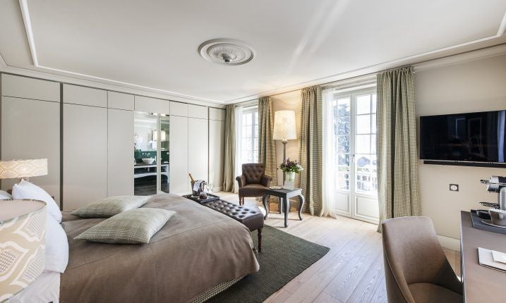 Elegant Swiss luxury hotel room with plush white bedding, contemporary design, large windows, and mountain-inspired neutral color palette in Gstaad