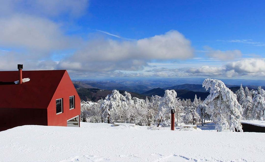 Luxurious mountain retreat with sleek white exterior, nestled in Serra da Estrela, blending contemporary design with rugged Portuguese landscape