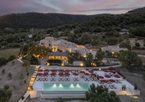 Luxurious stone-built Mediterranean villa with terracotta roof, surrounded by lush greenery and azure swimming pool in scenic Mallorca landscape