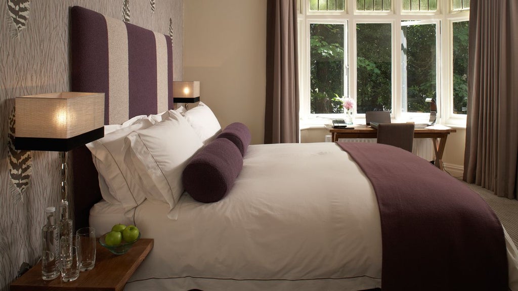 Elegant green-themed hotel room with modern decor, plush bed, soft lighting, and sophisticated furnishings showcasing minimalist UK luxury accommodation design