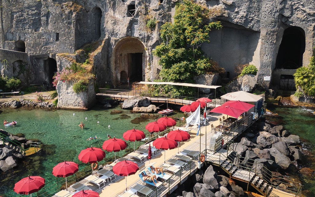 Luxurious cliffside hotel overlooking the Bay of Naples, with elegant Mediterranean architecture and breathtaking Sorrento coastline vista at sunset