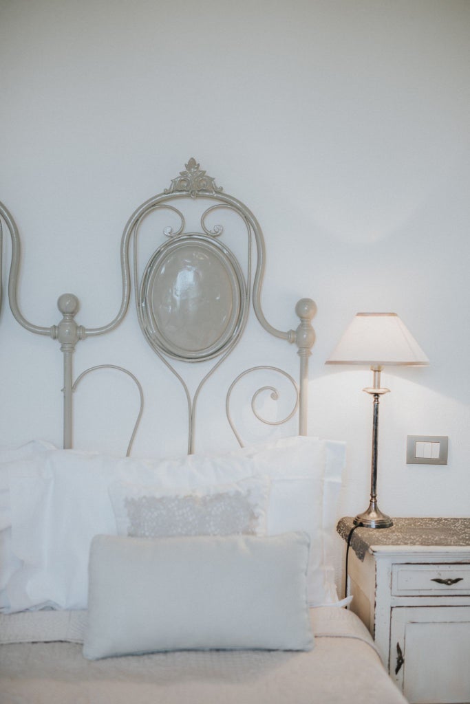 Elegant blue-toned luxury hotel room with crisp white linens, minimalist design, large windows overlooking Italian coastal landscape, and sophisticated decor