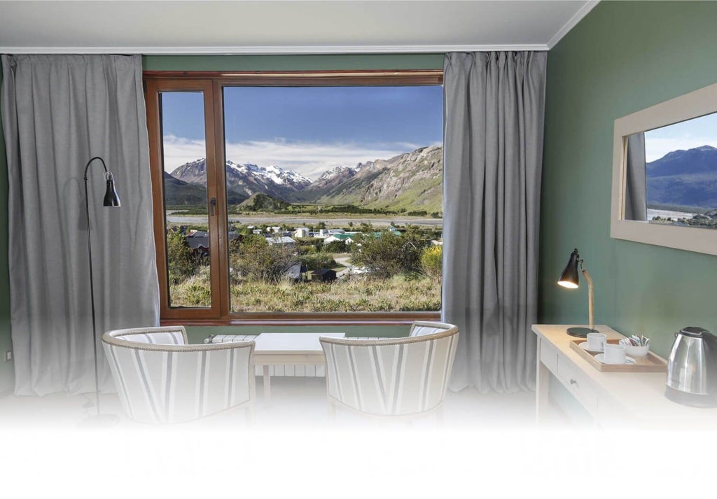 Elegant superior hotel room with modern design, plush white bedding, wooden accents, and large windows overlooking lush Argentine landscape scenery