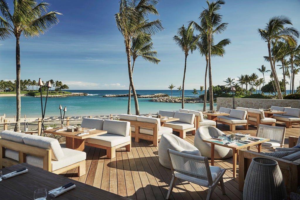 Beachfront luxury resort with infinity pools overlooking Pacific Ocean, surrounded by palm trees and pristine white sand beach