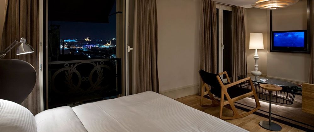 Luxurious king room at scenset Istanbul hotel with panoramic city views, modern minimalist design, plush bedding, and floor-to-ceiling windows overlooking urban landscape