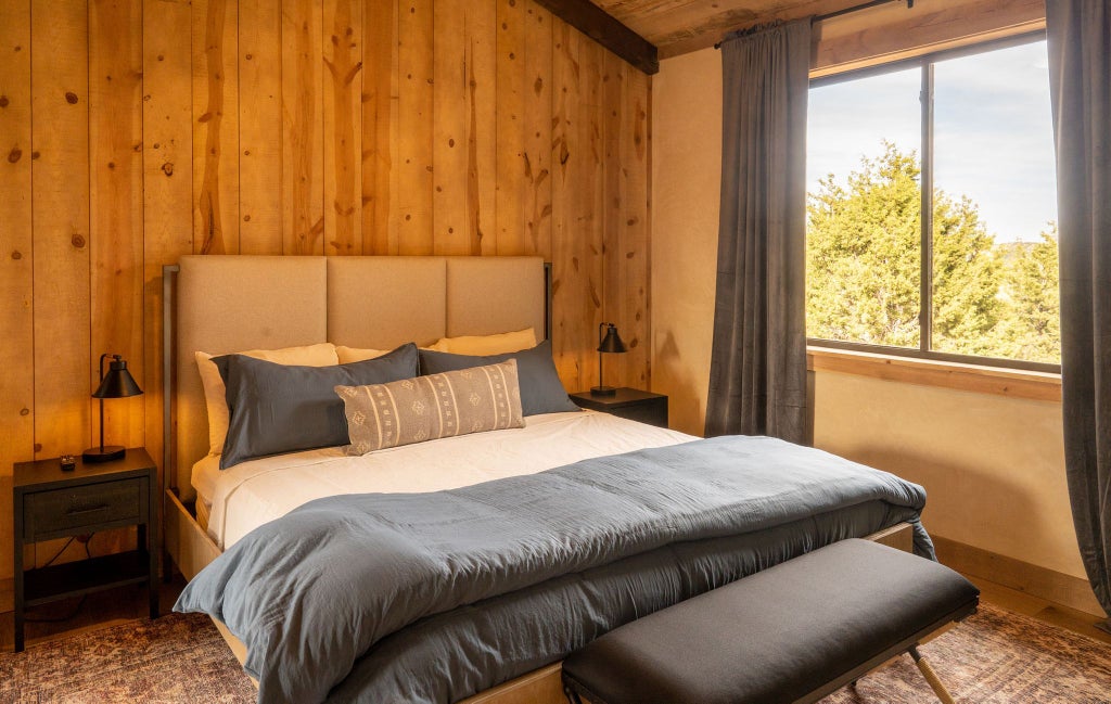 Spacious lodge room with rustic wooden furnishings, plush king bed, large windows overlooking scenic mountain landscape at scenic Mountain Ranch resort