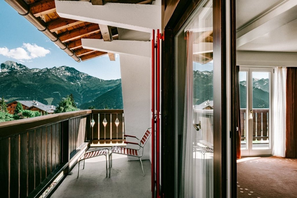 Luxurious alpine suite with panoramic mountain views, modern minimalist design, floor-to-ceiling windows, and elegant wood accents in Swiss chalet setting