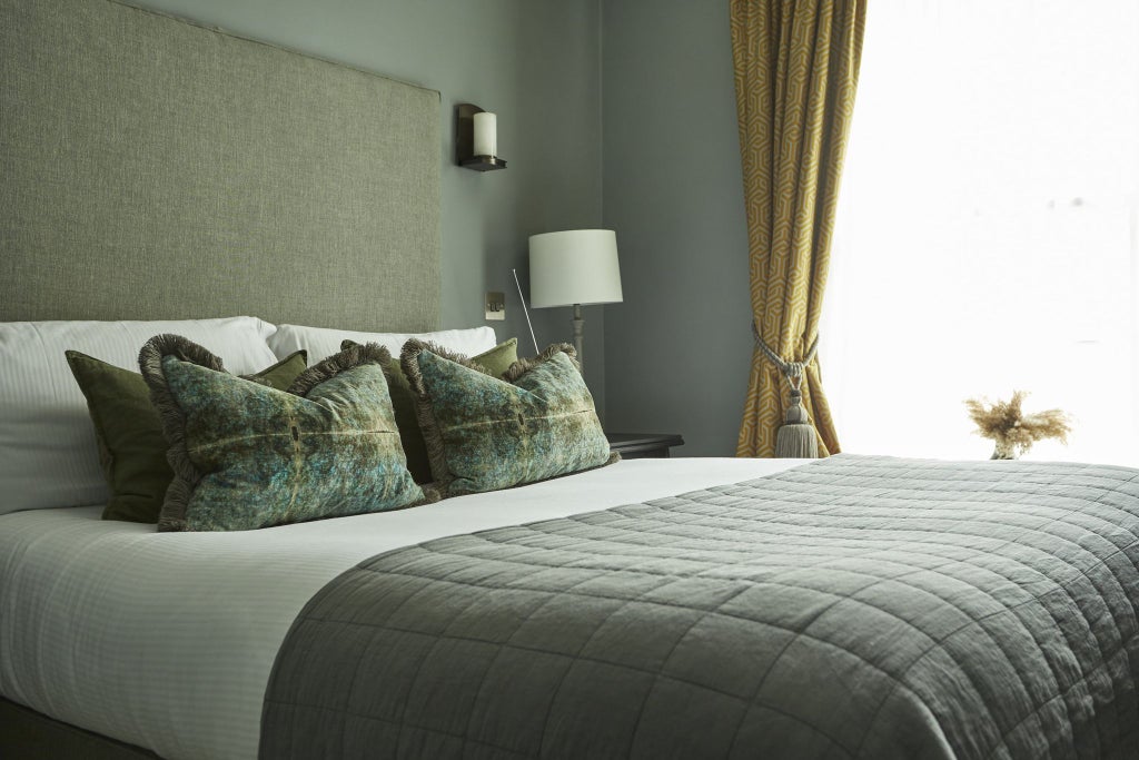 Elegant standard double hotel room with crisp white bedding, warm wood furnishings, and soft neutral tones in a sophisticated United Kingdom accommodation