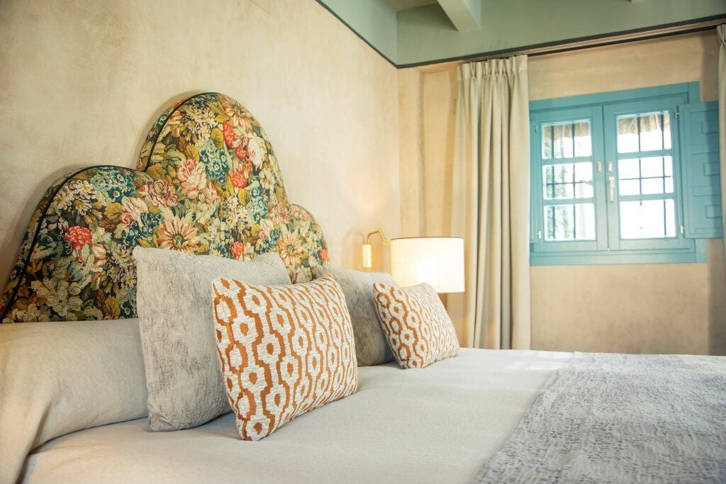 Elegant Spanish colonial-style deluxe hotel room with white walls, wooden furniture, crisp linens, and soft natural lighting in Seville