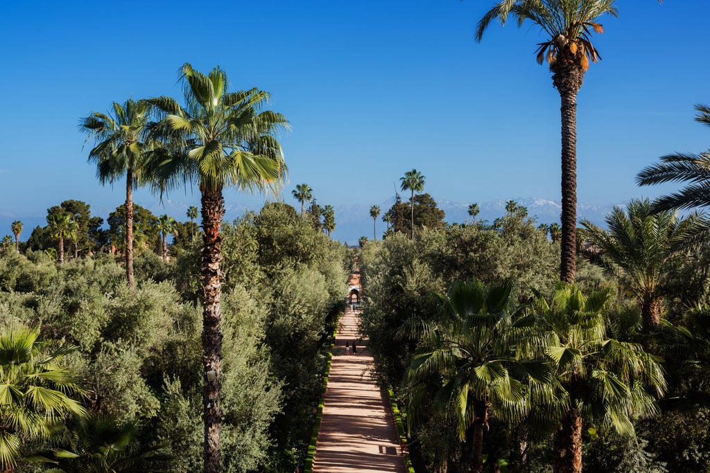 Historic Moroccan luxury hotel featuring ornate archways, traditional tilework, and manicured gardens with palm trees and reflecting pool