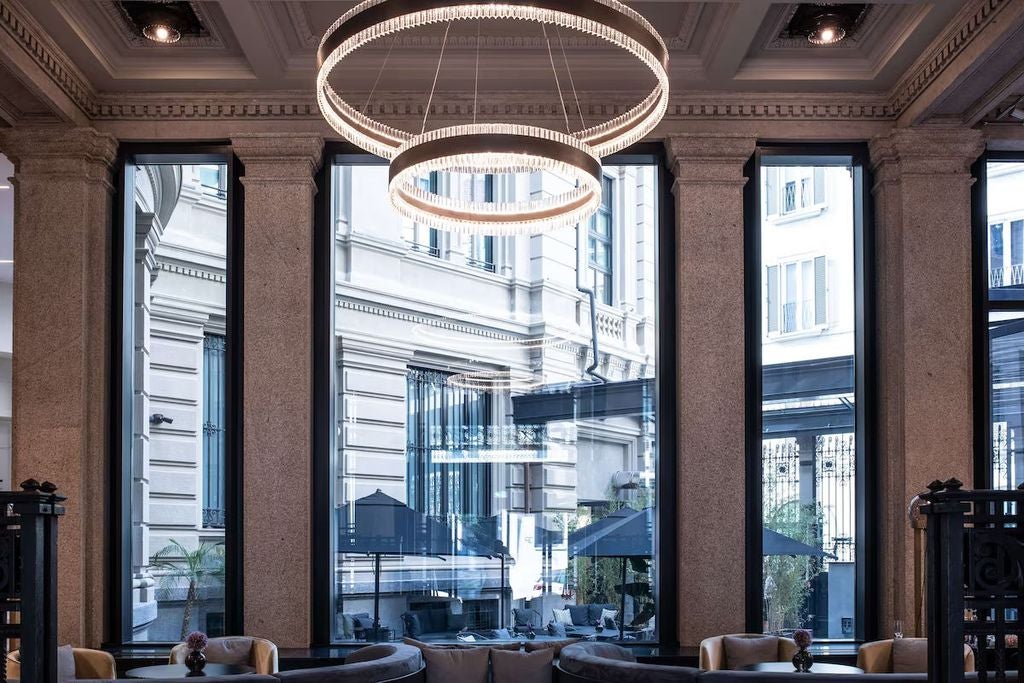 Elegant historic hotel facade in Milan featuring ornate Italian Renaissance architecture, classic arched windows and stone balustrades