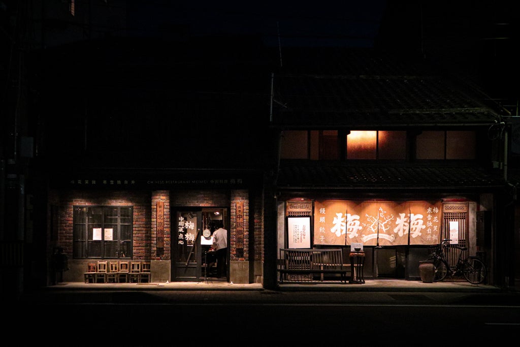 Traditional Japanese courtyard with ornate wooden architecture, stone pathway leading to a peaceful zen garden with manicured shrubs and lanterns