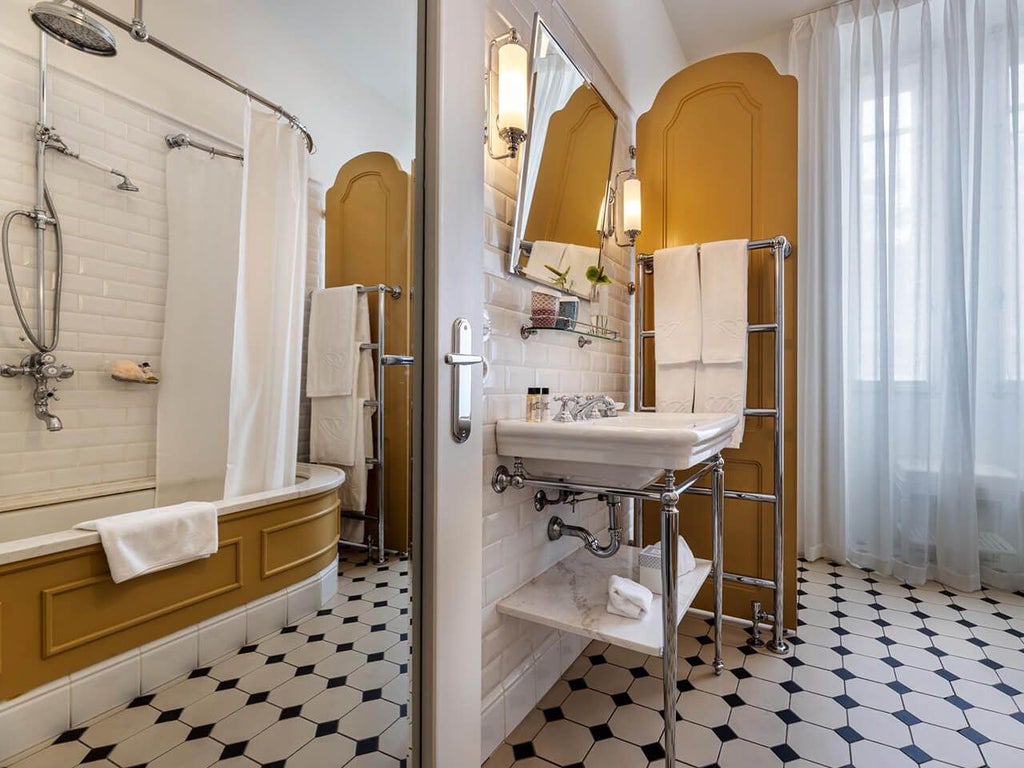 Elegant classic bedroom at Vidago Palace Hotel with ornate chandelier, plush cream-colored furnishings, and intricate period-style Portuguese decor