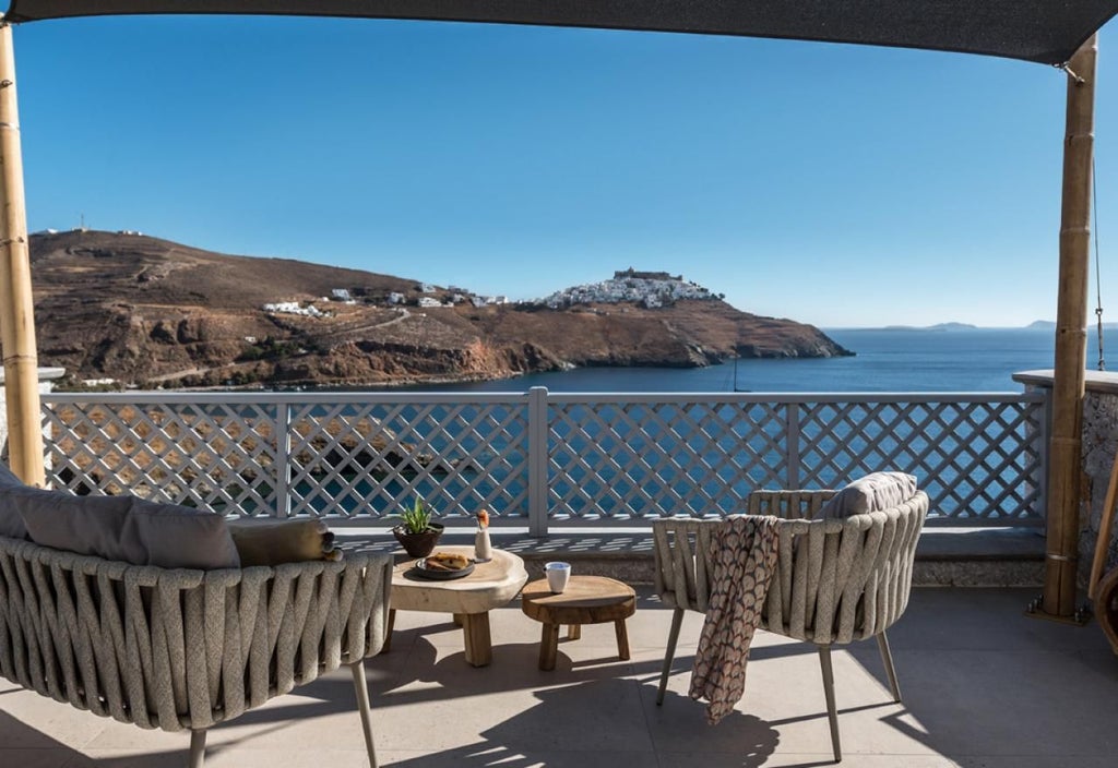 Luxurious honeymoon suite in Greece, featuring elegant white decor, minimalist design, and a stunning sea view from a private balcony overlooking the Aegean.