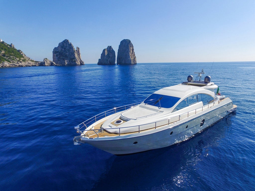 Modern luxury yacht with white exterior docked at Italian marina, featuring panoramic windows and sleek sunbathing deck