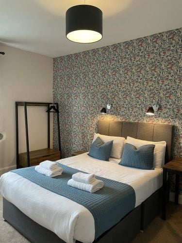 Luxurious hotel room at The Wheatsheaf Inn with plush bedding, rustic wooden furniture, and warm ambient lighting in a traditional United Kingdom setting