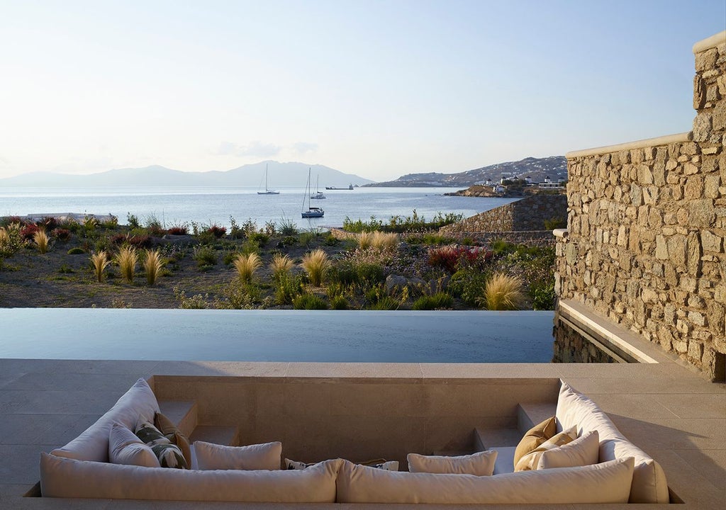 Luxurious one-bedroom villa with private heated pool overlooking azure Aegean Sea, featuring modern minimalist design and expansive Mykonos landscape views