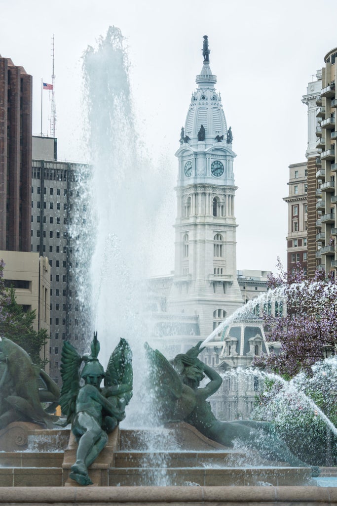 Elegant Four Seasons Philadelphia hotel rises 60 stories with sleek glass exterior, illuminated against twilight sky, reflecting city lights