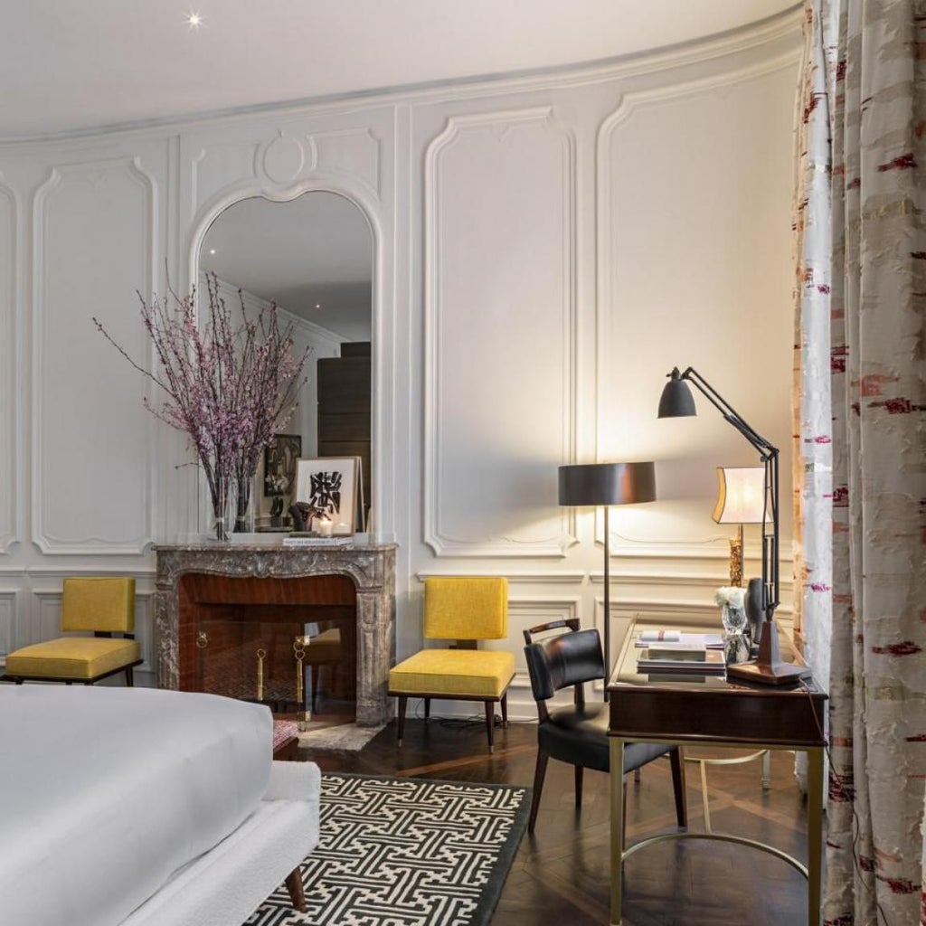 Elegant Parisian hotel interior with plush cream-colored armchairs, ornate golden details, and sophisticated marble fireplace showcasing luxurious French design