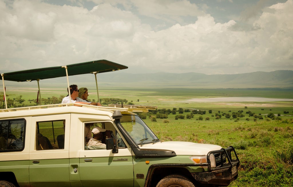 Luxury safari tent with private deck overlooking Ngorongoro Crater, featuring canvas walls and rustic-chic wooden furnishings at sunset