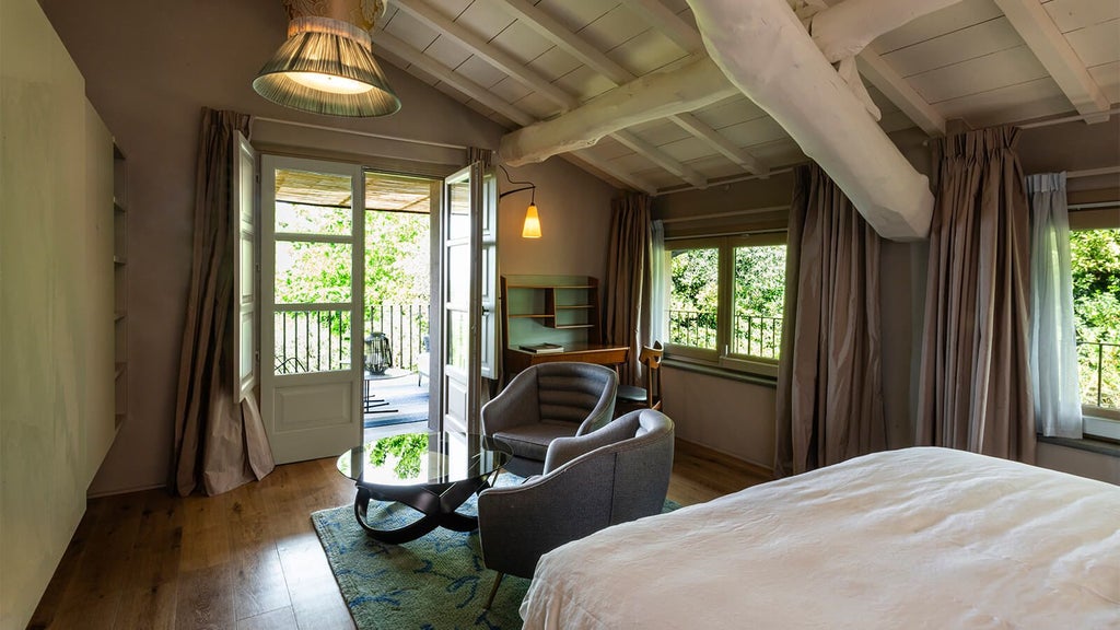 Elegant Tuscan-style bedroom with soft white linens, rustic wooden furniture, and panoramic view of rolling Italian countryside landscape