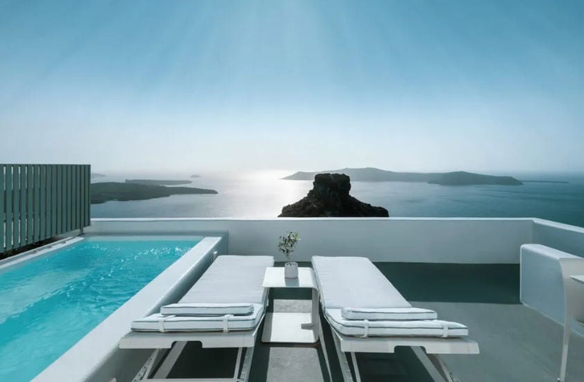 Elegant white-walled suite with private infinity plunge pool overlooking Santorini's caldera, featuring minimalist Greek design and sea views