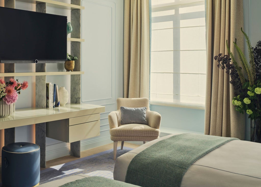 Elegant deluxe hotel room at One Aldwych with plush white bedding, modern decor, soft lighting, and city-view windows in a sophisticated London setting