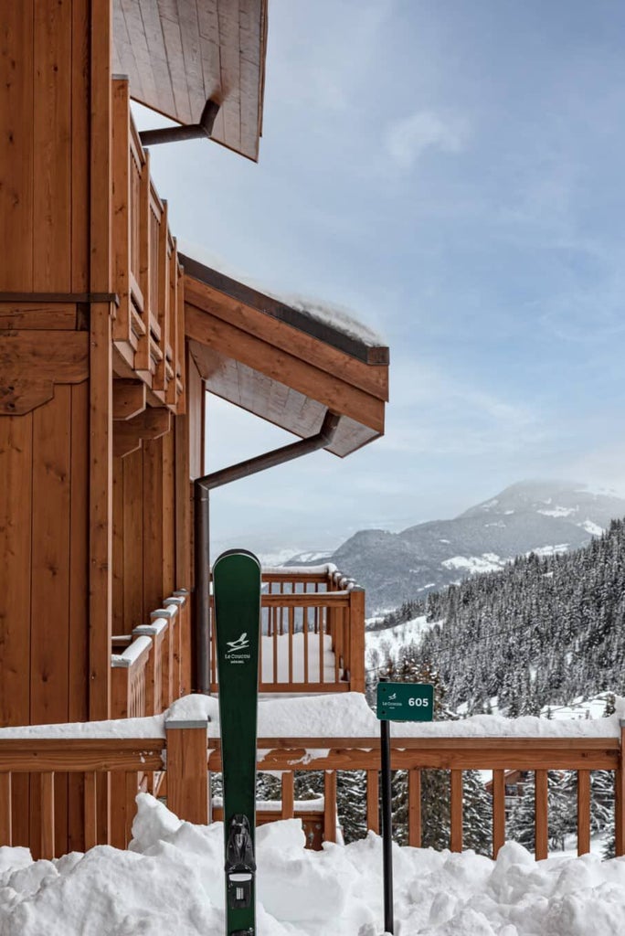 Luxurious alpine chalet-style hotel nestled in snowy Méribel mountains, featuring elegant wooden facade and expansive panoramic windows against pristine winter landscape