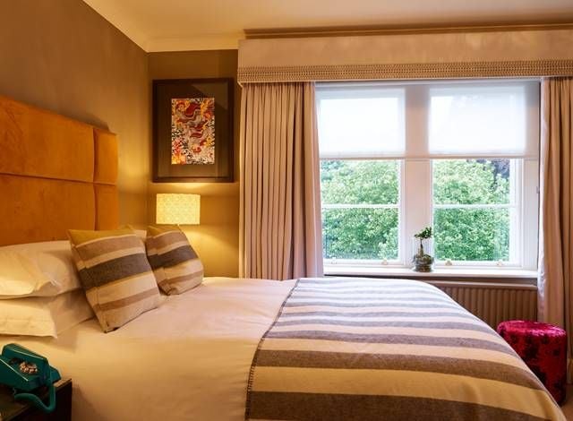 Elegant compact double room with modern minimalist decor, soft neutral tones, plush bedding, and chic urban design elements highlighting compact luxury accommodations.