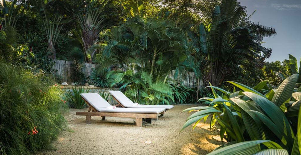 Elevated beachfront lodge with thatched-roof bungalows nestled in lush hillside overlooking pristine Madagascar bay and white sand beach