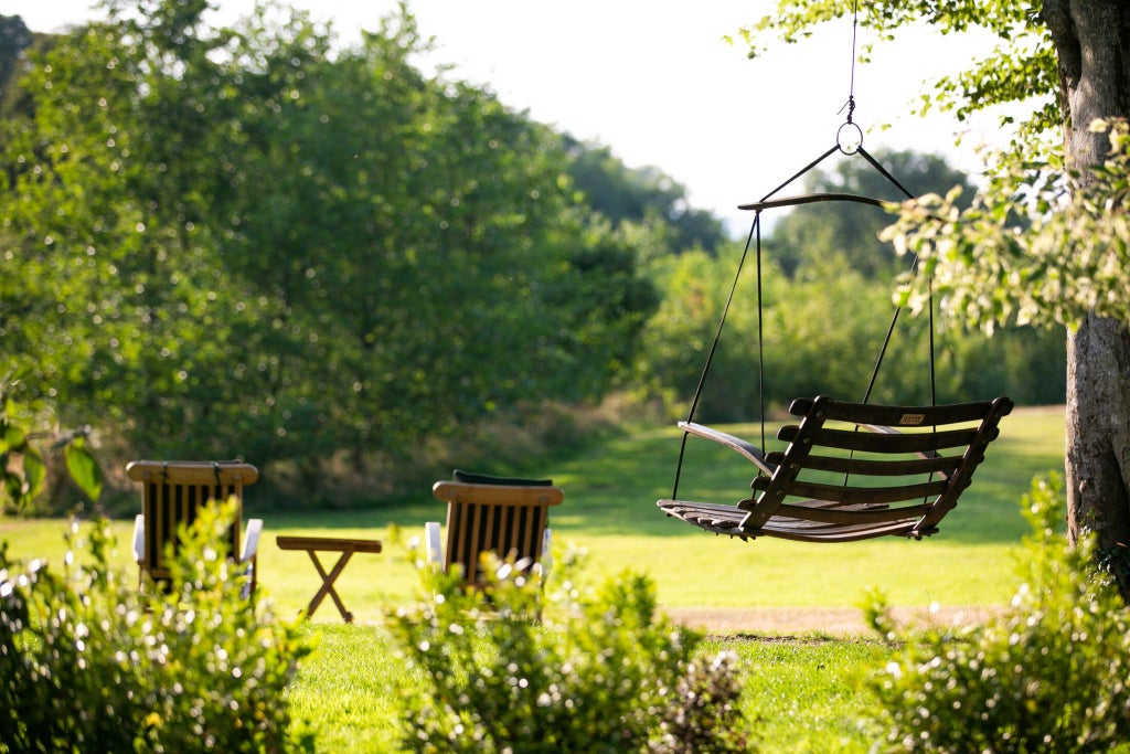 Elegant country house hotel nestled in lush Pembrokeshire countryside, with stone exterior, manicured gardens, and soft natural lighting highlighting rustic luxury