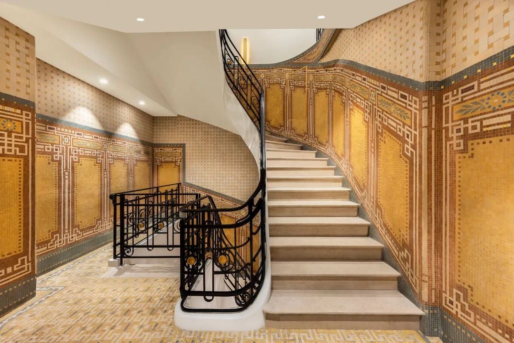 Elegant Parisian hotel façade with ornate stone carvings, wrought-iron balconies, and classic French windows under soft evening lighting