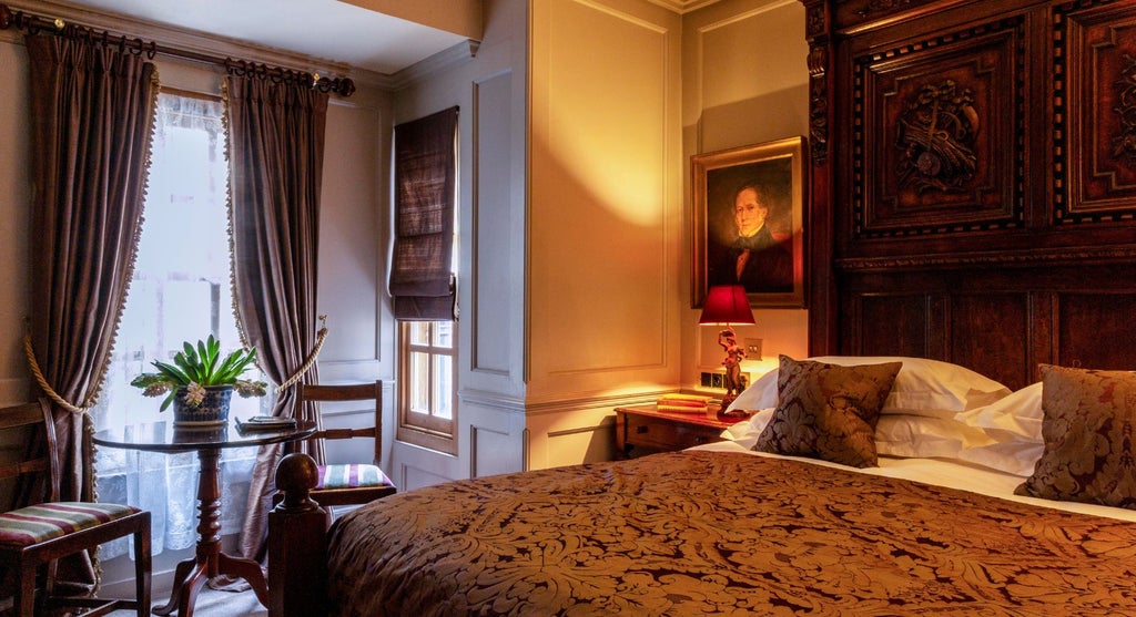 Elegant club double hotel room with plush dark leather headboard, antique wooden furnishings, soft ambient lighting, and refined British aesthetic at Scenset accommodation