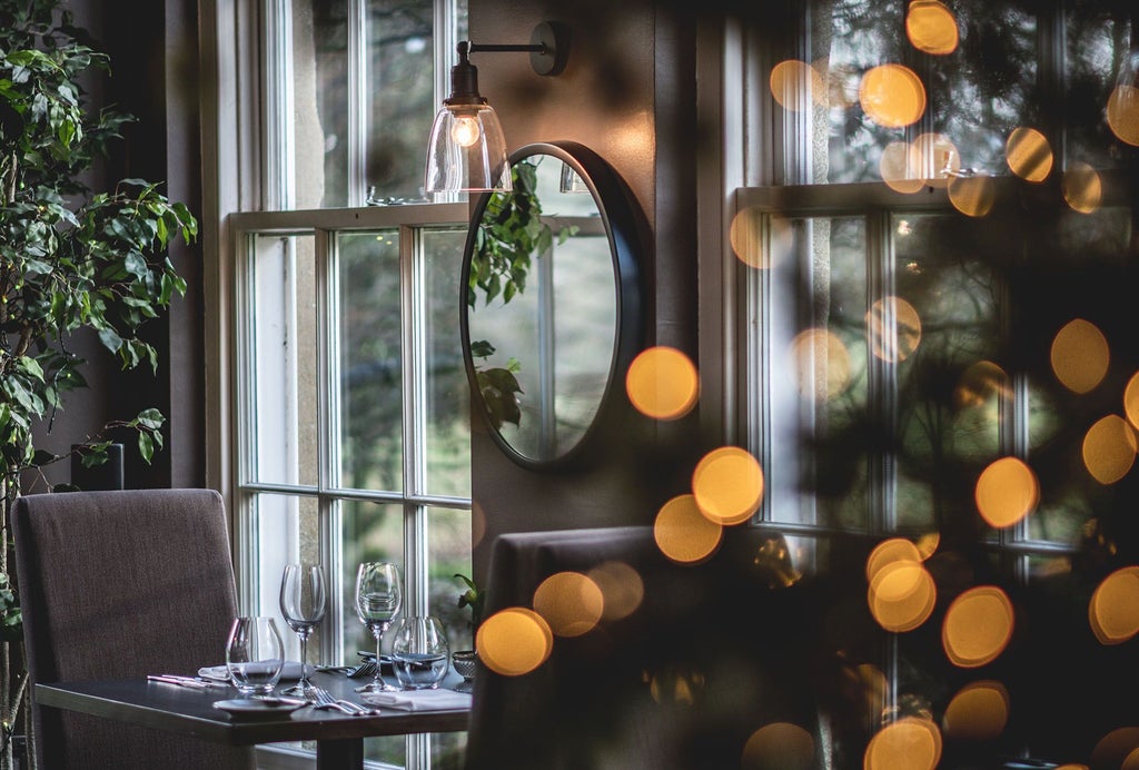 Elegant stone country house hotel nestled in Yorkshire Dales, featuring stone facade, manicured gardens, and sophisticated architectural details against scenic landscape backdrop.