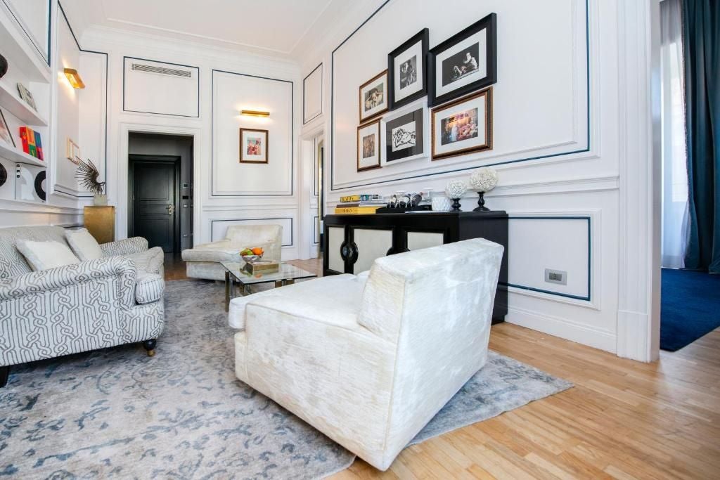 Elegant Dama Suite in Palazzo Dama, featuring luxurious white marble, plush king bed, and expansive city view through floor-to-ceiling windows in Rome, Italy