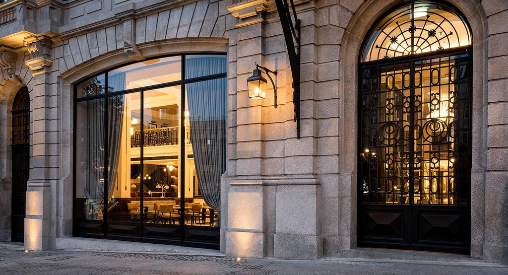 Elegant Art Nouveau facade of historic luxury hotel in Porto, featuring ornate gilded details and grand Belle Époque architectural style against soft evening light