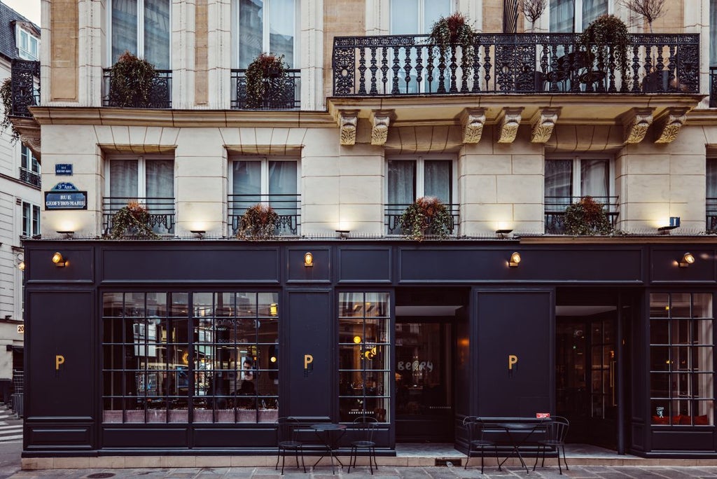 Elegant Art Deco hotel facade with ornate balconies, vibrant burgundy exterior, and classic Parisian architectural details in charming urban setting