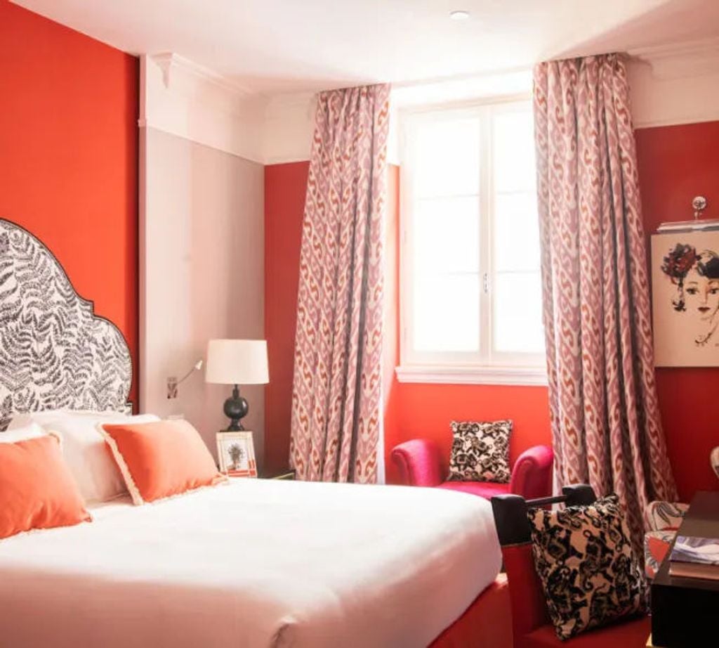 Elegant hotel room with teal velvet headboard, white linens, gold accents, vintage-style artwork and crystal chandelier in Rome