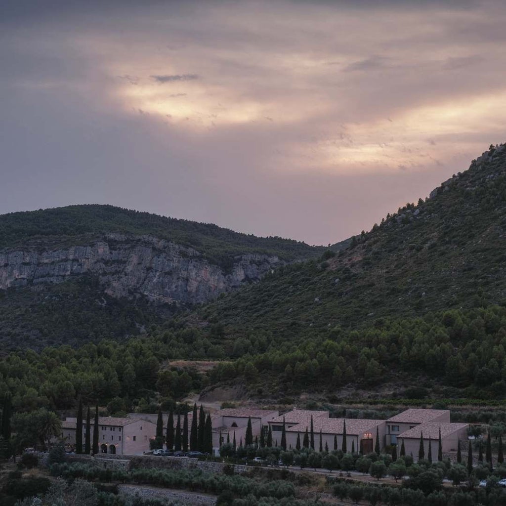 Luxurious stone winery hotel nestled in scenic Spanish vineyard with rustic architecture, stone walls, and rolling countryside landscape