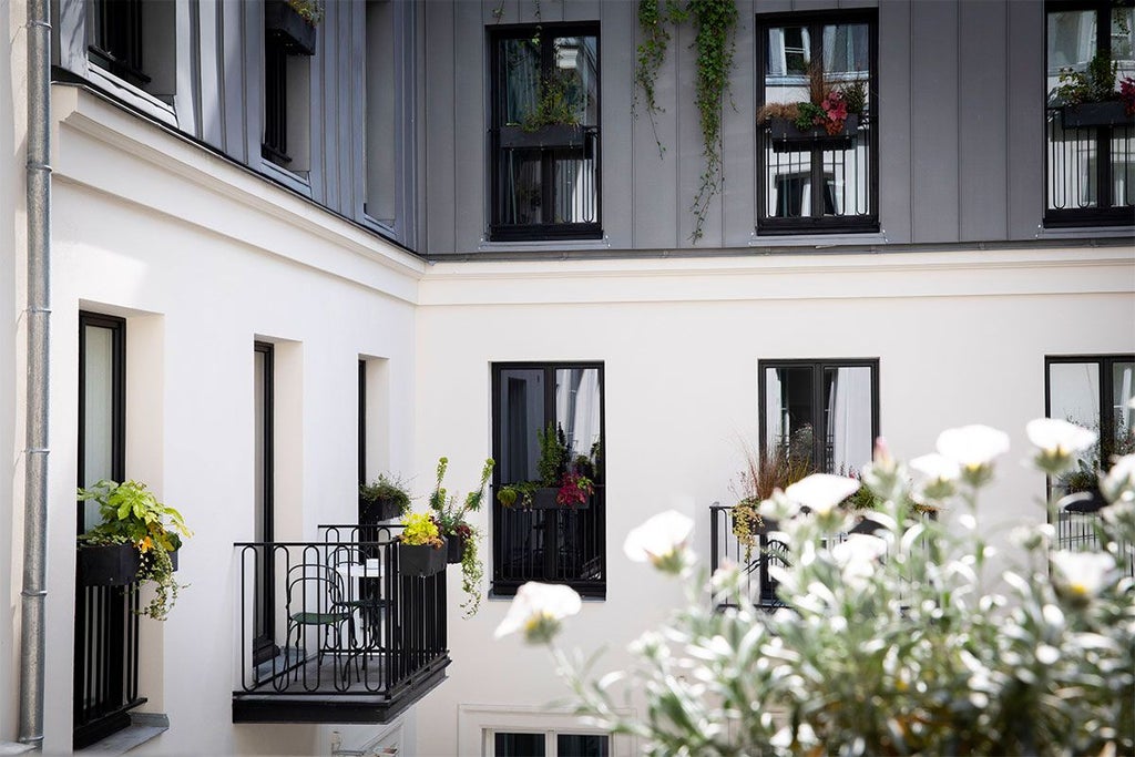 Elegant Parisian hotel room balcony with ornate wrought-iron railings overlooking a charming boulevard, soft daylight illuminating classic French architectural details